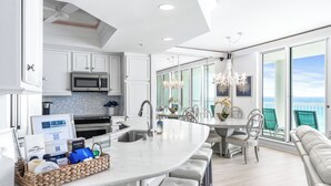 A modern kitchen with a large island, white cabinetry, and a view of the ocean. - 2026 Updated, 5-Star, Modern Beachfront Condo at Silver Beach Towers (Destin)