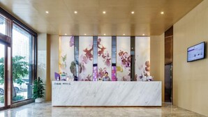 A reception desk with a marble top, a large window on the left, and a wall-mounted TV on the right. - Lavande Hotel (Guangzhou)