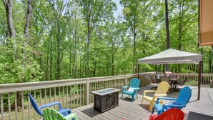 A deck with outdoor furniture and a fire pit, surrounded by a forest. - ‘The Lake Place’ Cabin w/ Golf Cart & Free Kayaks! (Lavonia)