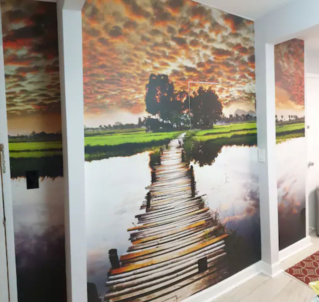 A corridor with a mural of a sunset over a river with a wooden dock.