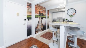 Une cuisine moderne avec des meubles blancs, un îlot central doté de tabourets et une grande horloge murale.