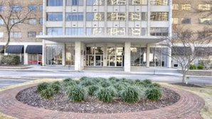 Un bâtiment moderne dot é d’une entrée centrale, entouré d’un jardin aménagé avec un chemin en briques.