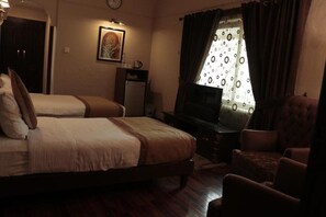 A hotel room with two beds, a television, a desk, and a chair.
