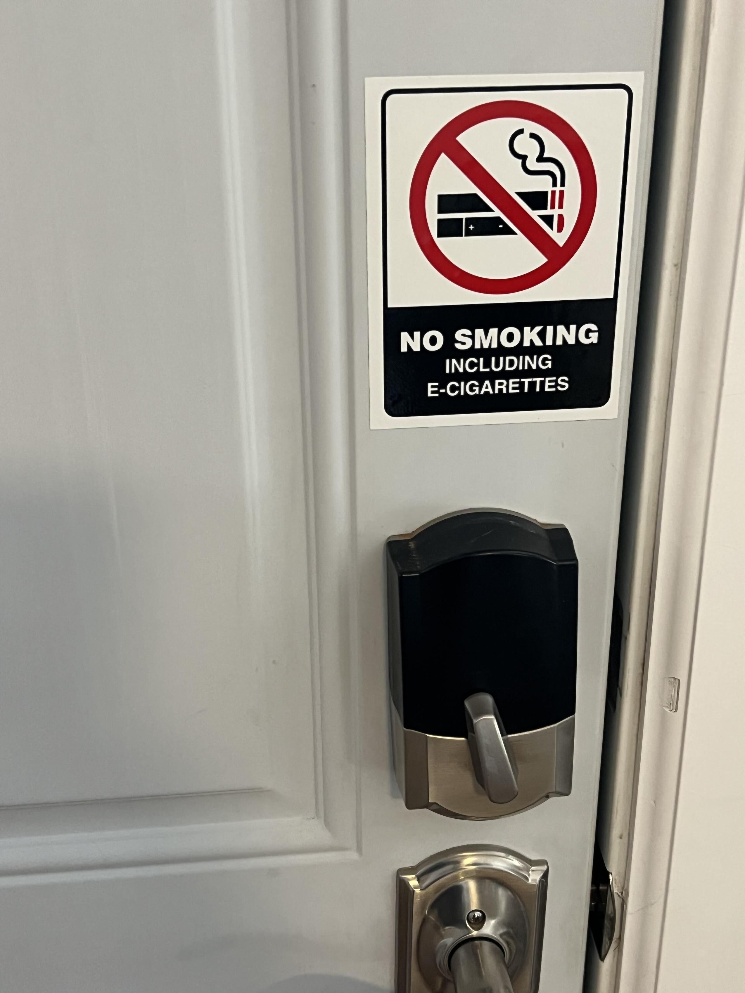 Une porte avec un panneau « interdiction de fumer » et un lecteur de carte magnétique.
