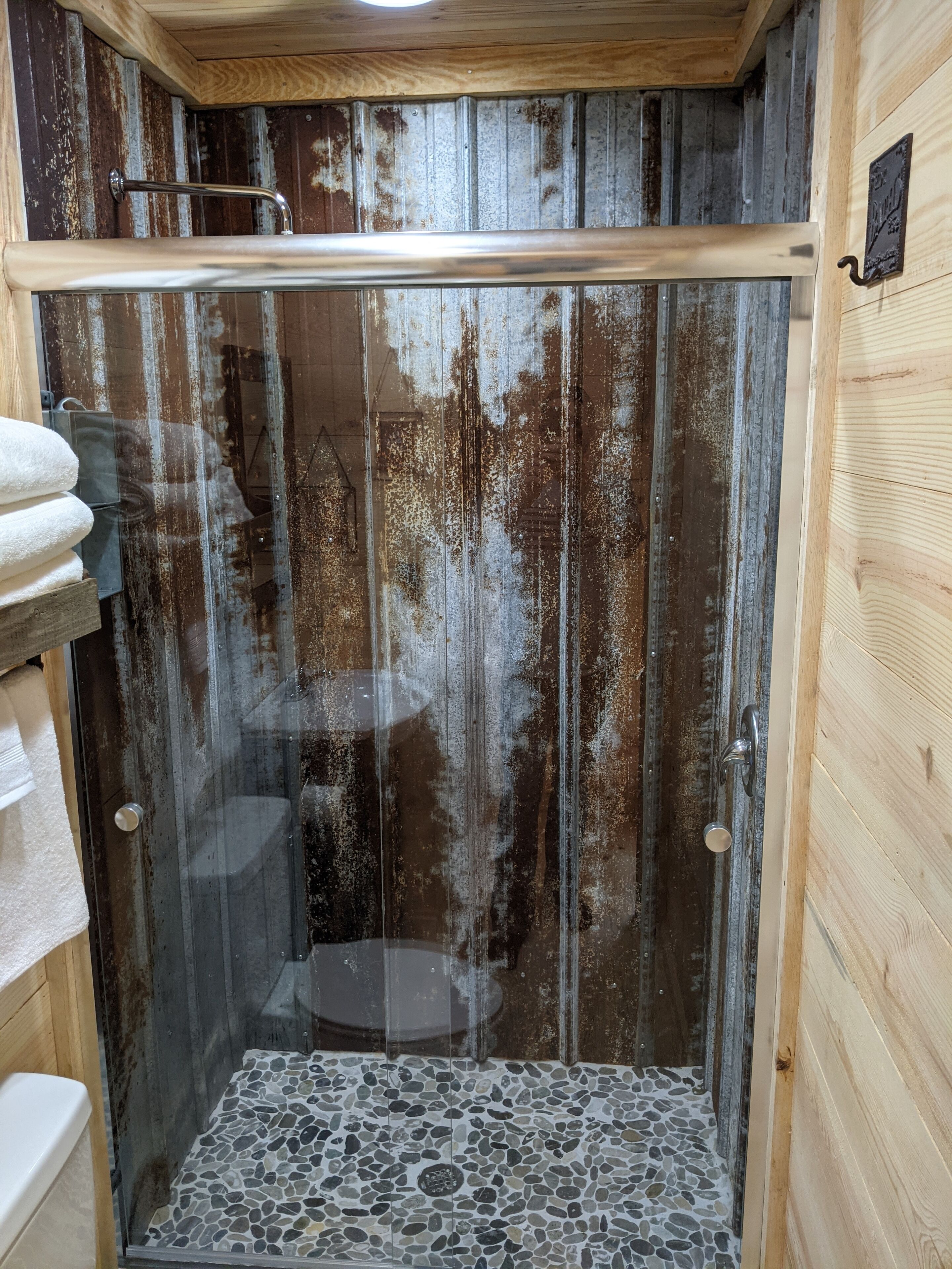 A shower with a glass door, a wooden interior, and a mosaic floor.