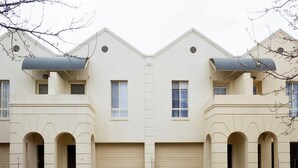 A symmetrical building with two garage doors, a central entrance, and a small mailbox. - Adelaide | 3BR Norwood Townhouse | Fringe Stay + Wi-Fi + Parking + Smart TV | Walk Everywhere (Norwood)