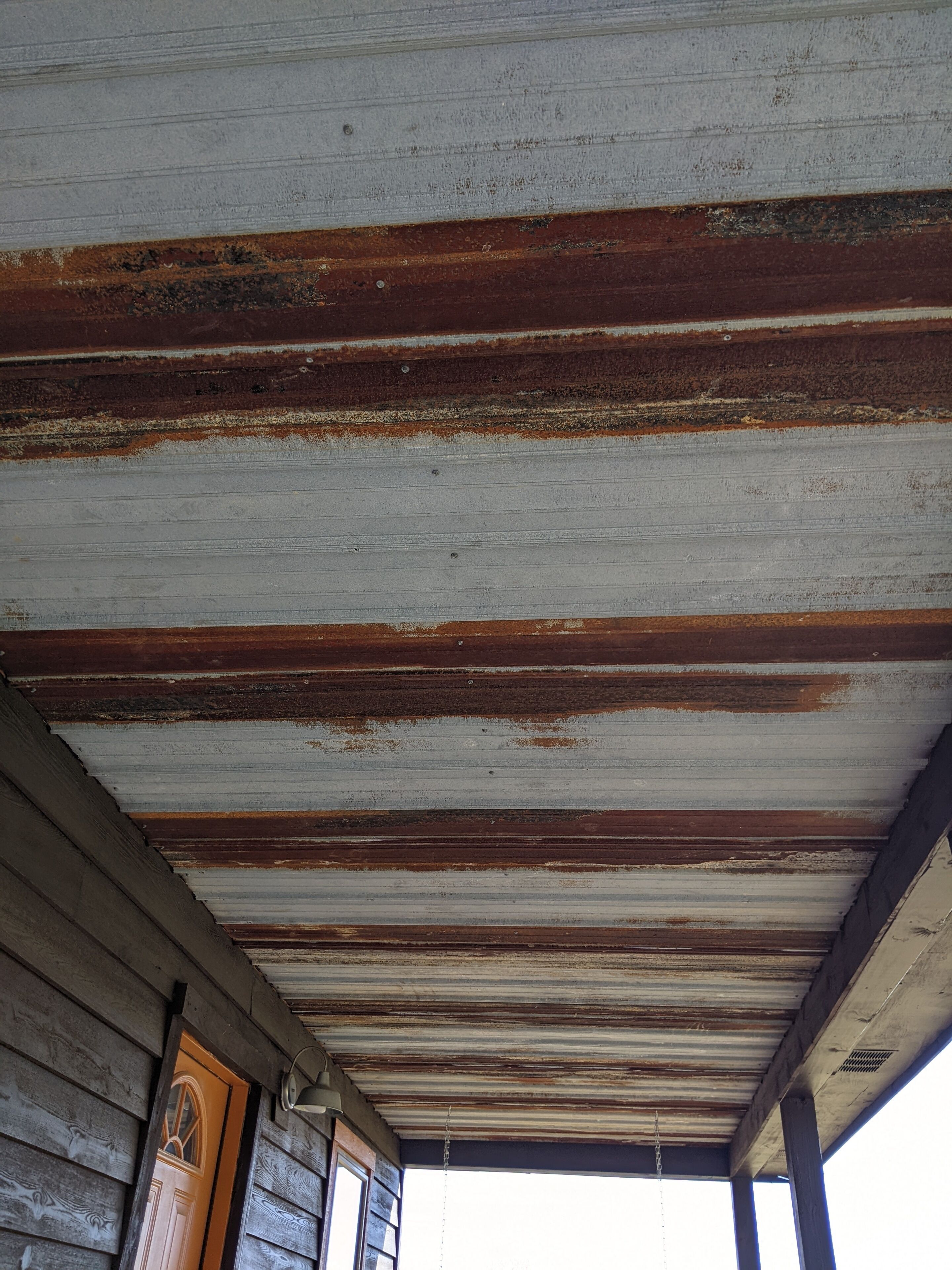 A rustic wooden structure with a corrugated metal roof and a wooden door.