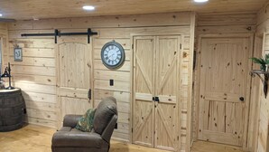 A wooden interior with a leather sofa, wooden doors, and a clock on the wall.