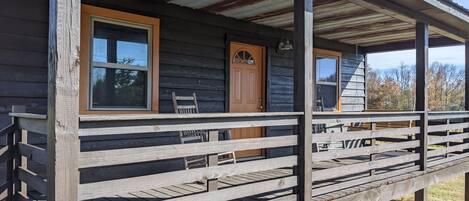 A rustic wooden cabin with a porch, a door, and windows.