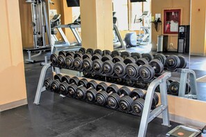 Une salle de sport équipée de rangées d’haltères, de tapis de course et d’autres appareils de musculation.