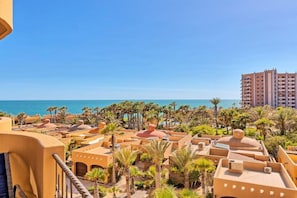 Ein Küstenresort mit mehreren Gebäuden, Palmen und freiem Blick auf das Meer.