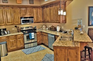 Eine Küche mit Holzausstattung, Granit Arbeitsplatten, Edelstahlgeräten und einer Bar mit Hockern.