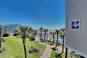Un hotel con piscina, palmeras y un cielo azul despejado.