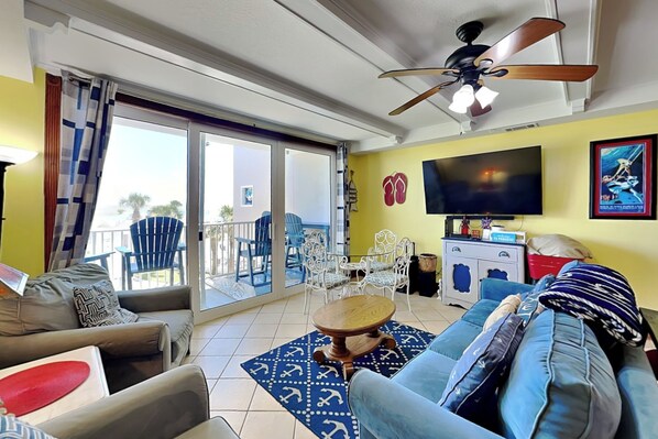 A living room with a sofa, armchairs, a coffee table, a TV, and a ceiling fan.