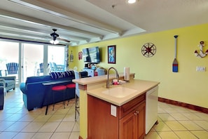 A kitchen with a sink, a television, and a ceiling fan. - Pet friendly condo w. community pool + partial ocean views! (Tybee Island)