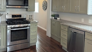 A modern kitchen with stainless steel appliances, light green cabinetry, and a wooden floor. - Cozy Flagstaff Home w/ Outdoor Fire Place (Flagstaff)