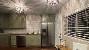 A spacious kitchen with wooden flooring, green cabinets, stainless steel appliances, and pendant lighting. - Cozy Flagstaff Home w/ Outdoor Fire Place (Flagstaff)