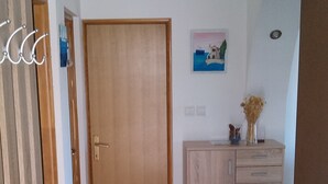 Un pasillo con una puerta de madera, un aparador con cajones y un pequeño cuadro en la pared.