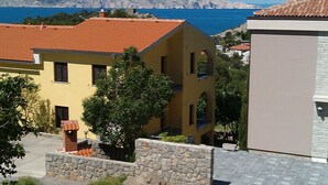 Un edificio amarillo con techo de tejas rojas, paredes de piedra y vista al mar.