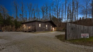A wooden lodge with a gravel driveway and a wooden fence. -  TURNING LEAF•Cozy Cabin in the RRG• Couples Retreat (Pine Ridge)