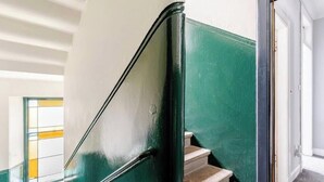 A staircase with a green handrail and a white wall. - Our Wee Getaway (Rothesay)