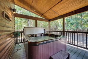 Eine Holzhütte mit Whirlpool und einer Terrasse.