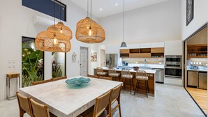 A modern kitchen with white cabinets, stainless steel appliances, and a central island with seating. - Eden Roc Villa Luxury 5BR in Hacienda Pinilla (Tamarindo)