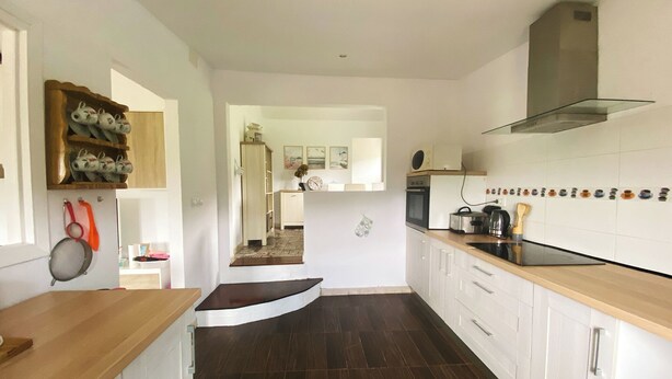 Une cuisine moderne avec un plancher en bois foncé, des armoires blanches et un comptoir en bois.