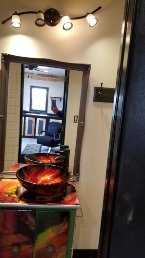 Een badkamer met een grote spiegel, een wastafel en een decoratieve schaal.