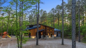 Une cabane moderne dotée d’une grande terrasse, entourée de grands arbres.