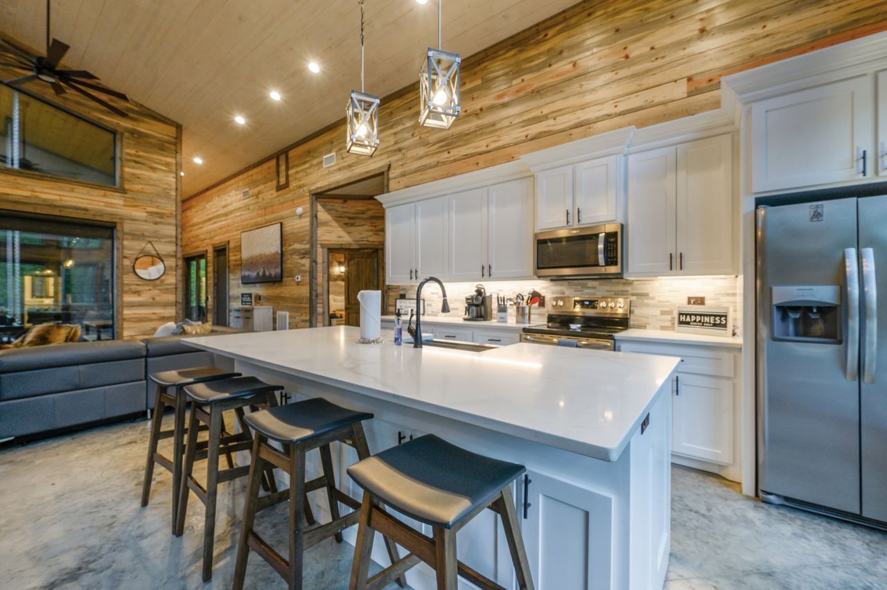 Una cocina moderna con armarios blancos, electrodomésticos de acero inoxidable y una isla grande con taburetes de bar.