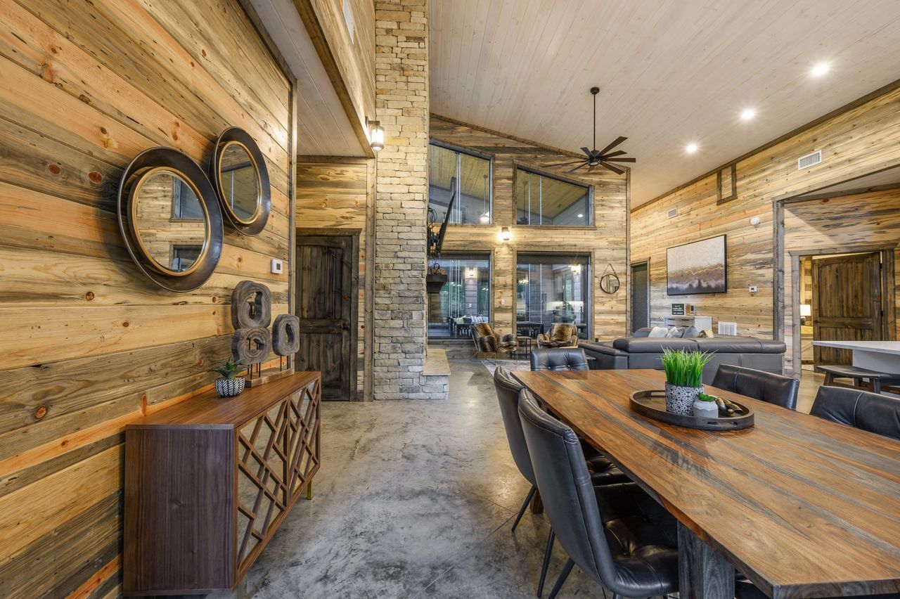 A spacious room with a long wooden table, leather chairs, and a stone accent wall.