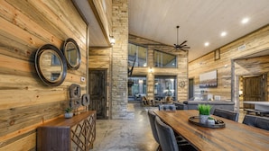Une pièce spacieuse avec une longue table en bois, des fauteuils en cuir et un mur décoratif en pierre.