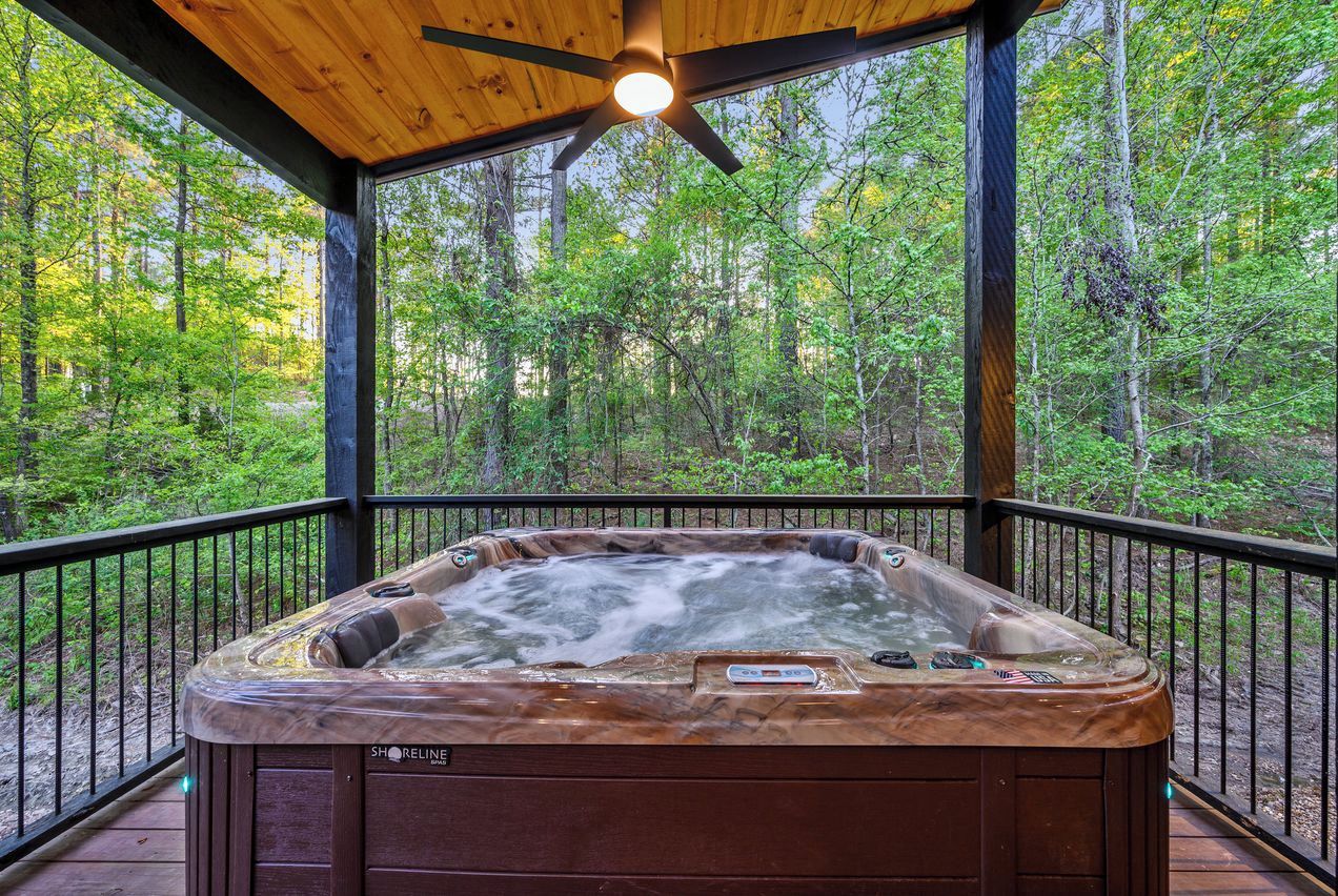 Un bain à remous sur une terrasse en bois, avec vue sur la forêt.