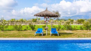 A swimming pool with two blue lounge chairs and a thatched umbrella. - Son Bordoi by Interhome (Moscari)