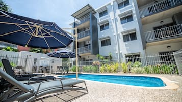 Een buitenzwembad, parasols voor strand/zwembad