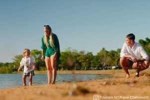 Uma família perto de um lago sob um céu claro.