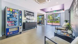 Una zona d'entrada moderna amb màquina expenedora, taulell de recepció i zona de seients amb vista a l'exterior.