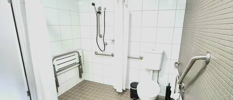A bathroom with a shower, toilet, and grab bars.