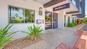The exterior of a hotel with a modern design, featuring a prominent 'Hudson' sign, a security camera, and a small garden area with plants and pebbles. - Hudson Parap (Parap)