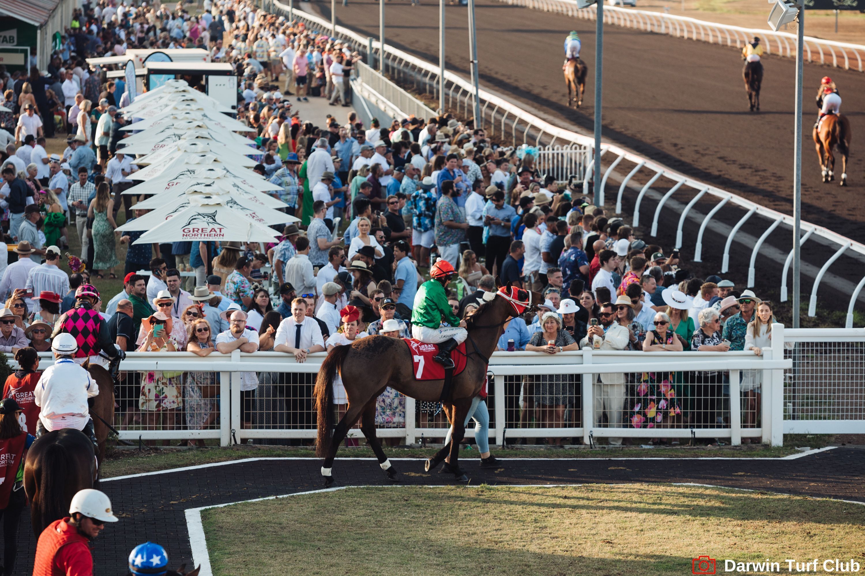 A horse race event with a crowd of spectators and jockeys on horses.