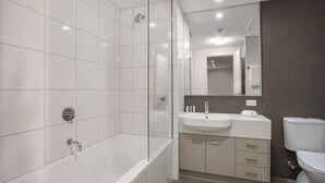 A modern bathroom with a bathtub, a sink, and a toilet. - Hudson Parap (Parap)