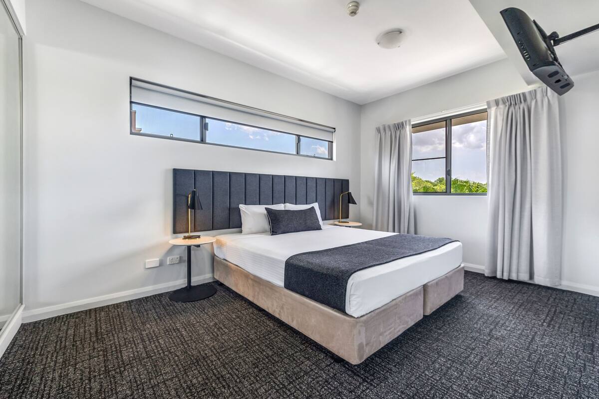 Habitación de hotel moderna con una cama grande, una ventana con cortinas, un ventilador de techo y vistas a zonas verdes.