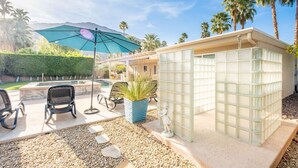 A pool area with a glass-enclosed hot tub, outdoor seating, and a large umbrella. - Relax in Palm Springs Pool, Spa, EV Charger, Views (Palm Springs)