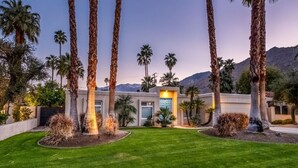 A modern house with a well-maintained lawn, tall palm trees, and a mountain backdrop. - Relax in Palm Springs Pool, Spa, EV Charger, Views (Palm Springs)