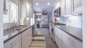A modern kitchen with stainless steel appliances, a central island, and a ceiling fan. - Relax in Palm Springs Pool, Spa, EV Charger, Views (Palm Springs)
