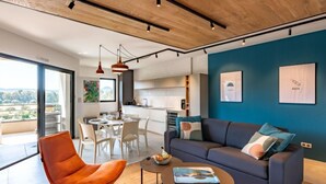 A modern living room with a dark blue accent wall, a grey sofa, and an orange chair. - Stanatura by Interhome (Porto Vecchio)