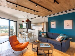 A modern living room with a dark blue accent wall, a grey sofa, and an orange chair. - Stanatura by Interhome (Porto Vecchio)