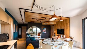 A modern living space with a dining area, a sofa, and a kitchen area. - Stanatura by Interhome (Porto Vecchio)