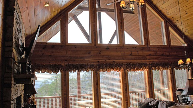 A spacious room with a high ceiling, large windows, and a ceiling fan.